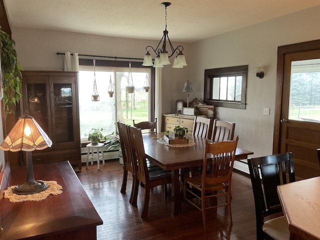 dining room with a baseboard radiator, dark wood-type flooring, and an inviting chandelier