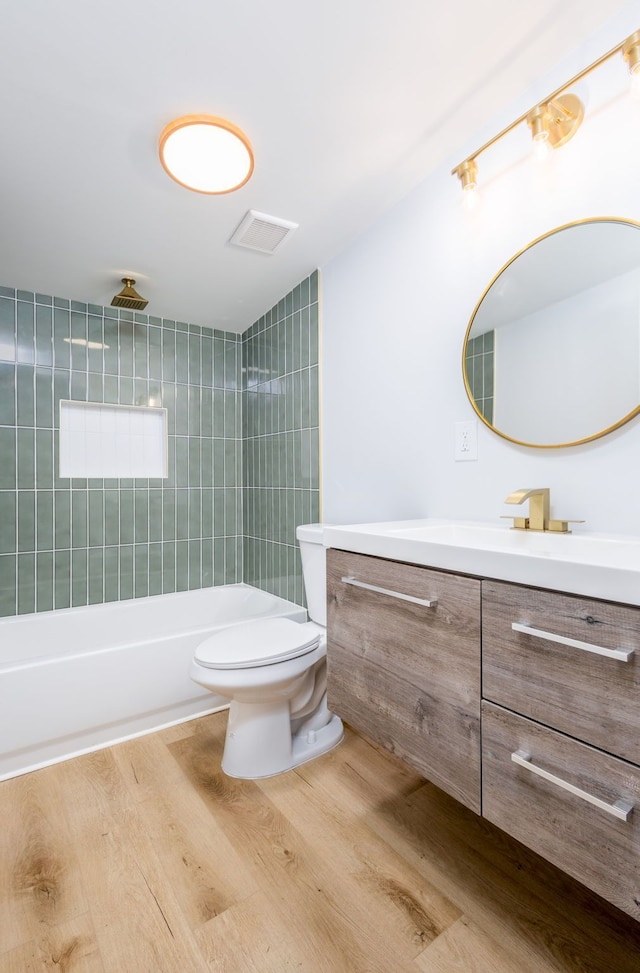 full bathroom featuring hardwood / wood-style floors, vanity, toilet, and tiled shower / bath