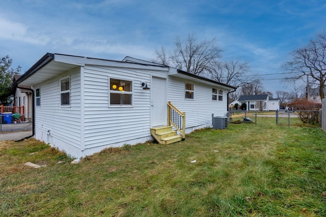 rear view of house featuring cooling unit and a yard