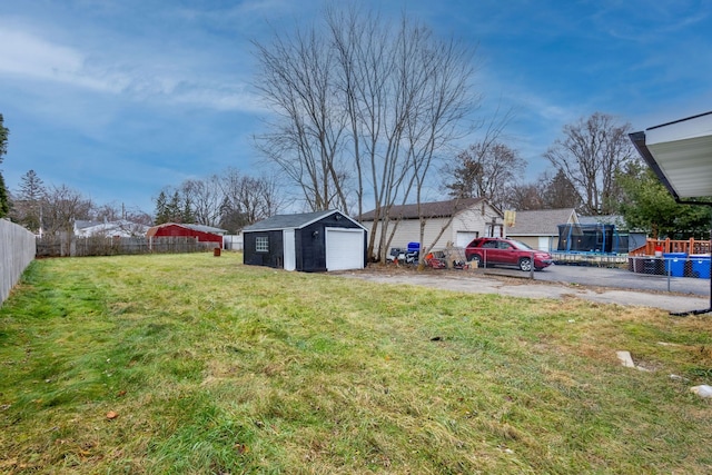 view of yard with an outbuilding, a garage, and a trampoline