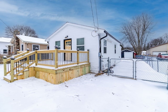 snow covered rear of property with a garage and an outbuilding