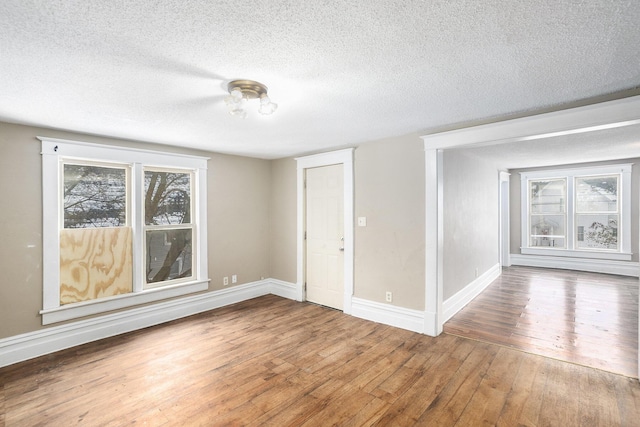 empty room with wood-type flooring and a textured ceiling