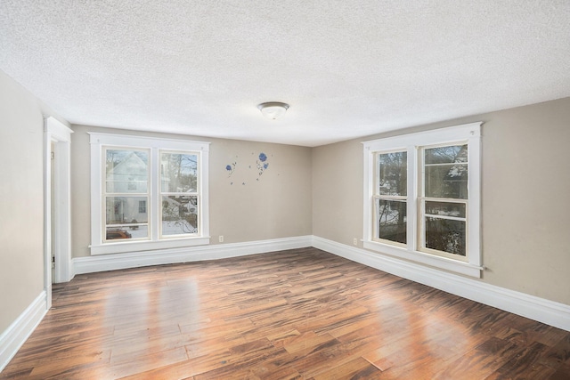 unfurnished room with dark hardwood / wood-style flooring and a textured ceiling