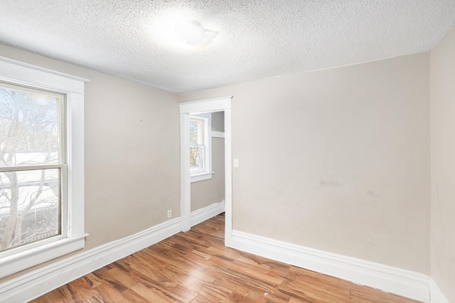 spare room featuring light hardwood / wood-style flooring, a healthy amount of sunlight, and a textured ceiling