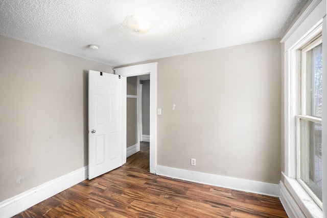 spare room featuring a textured ceiling and dark hardwood / wood-style floors