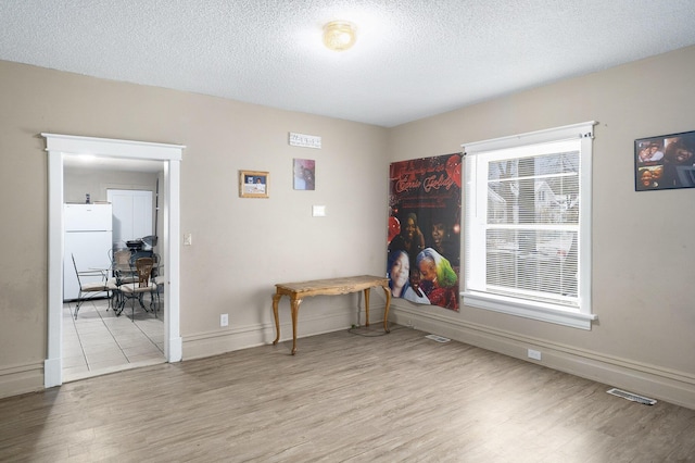 spare room featuring a textured ceiling and light wood-type flooring