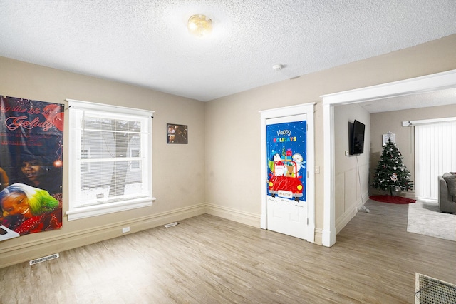 empty room featuring hardwood / wood-style floors, a healthy amount of sunlight, and a textured ceiling