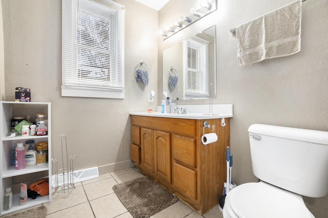 bathroom with tile patterned flooring, vanity, a healthy amount of sunlight, and toilet