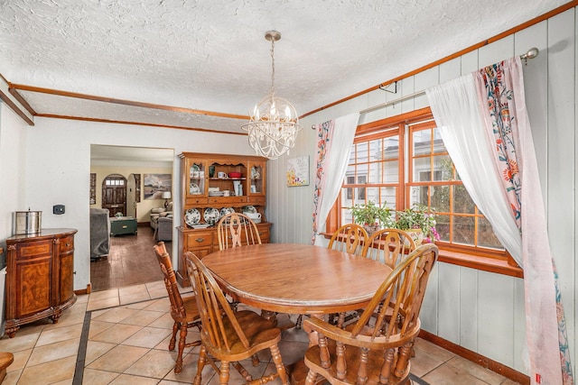 tiled dining room featuring a textured ceiling, crown molding, and a notable chandelier