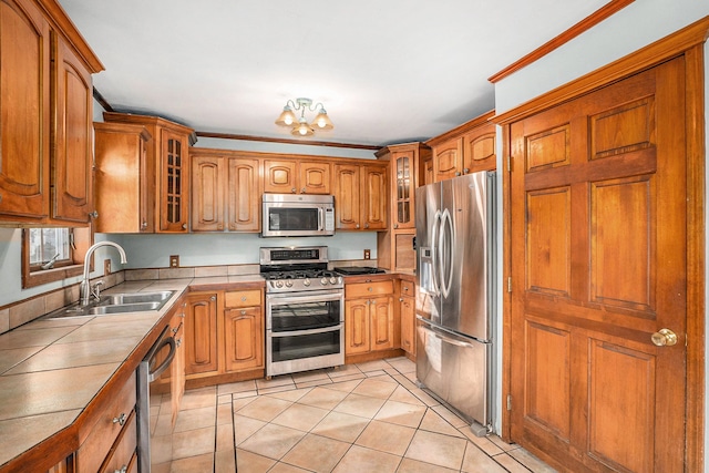 kitchen featuring stainless steel appliances, an inviting chandelier, crown molding, and sink