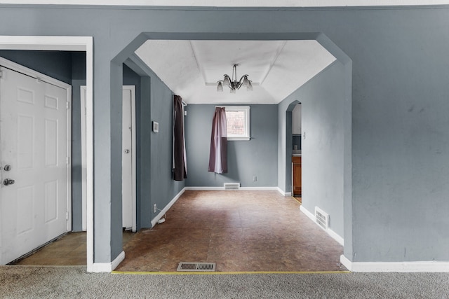 foyer entrance featuring dark colored carpet and an inviting chandelier