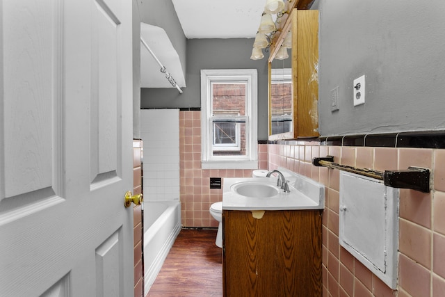 bathroom with toilet, vanity, tile walls, and hardwood / wood-style flooring