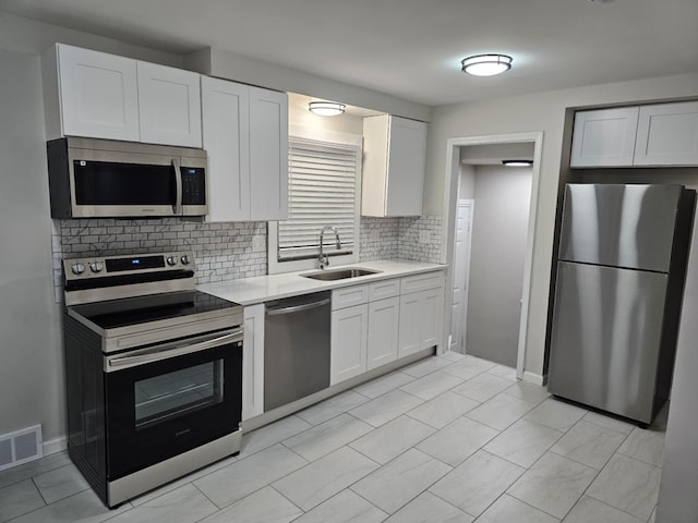 kitchen featuring white cabinetry, appliances with stainless steel finishes, sink, and backsplash