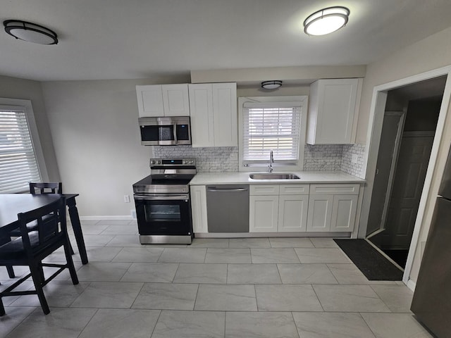 kitchen with stainless steel appliances, sink, a wealth of natural light, and white cabinets