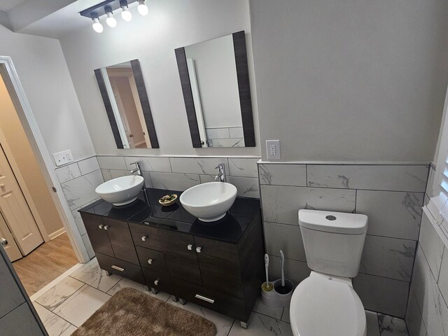 bathroom with vanity, tile walls, and toilet