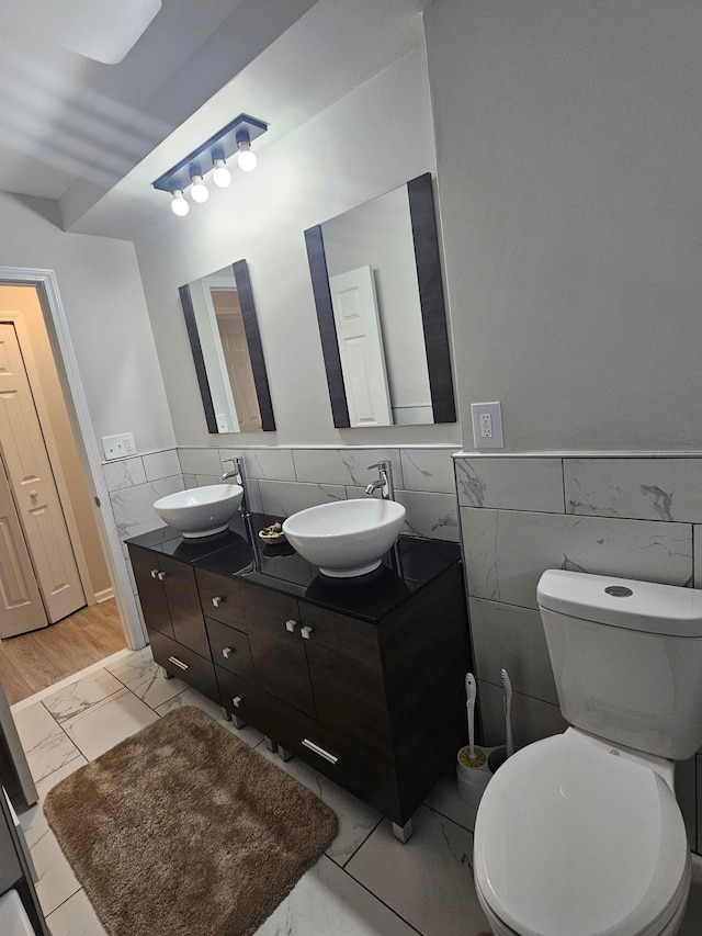 bathroom featuring vanity, tile walls, and toilet