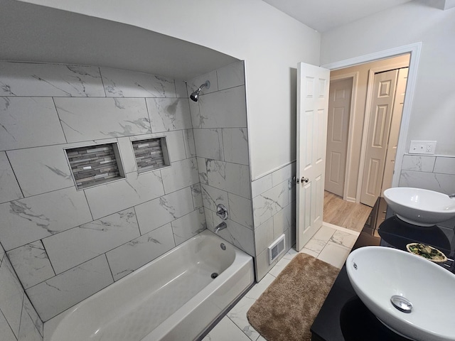 bathroom featuring tiled shower / bath, tile walls, and vanity