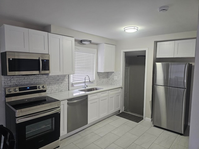 kitchen with stainless steel appliances, sink, white cabinets, and decorative backsplash