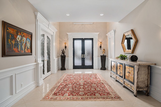 foyer featuring recessed lighting, french doors, light tile patterned floors, and a decorative wall