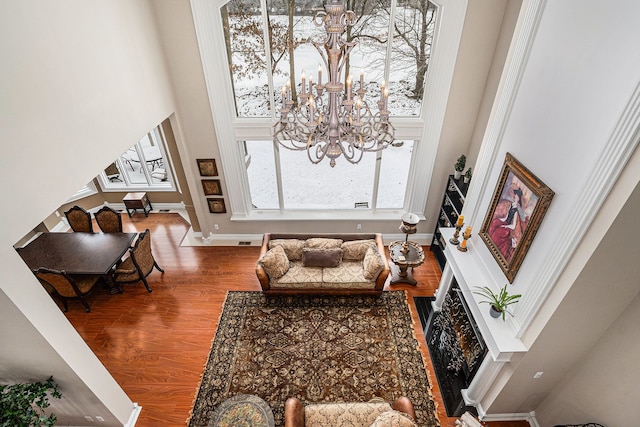 living area featuring a chandelier, wood-type flooring, and a towering ceiling