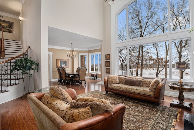 living room featuring crown molding, wood-type flooring, a high ceiling, and a notable chandelier