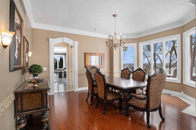 dining area featuring dark hardwood / wood-style flooring, ornamental molding, and an inviting chandelier