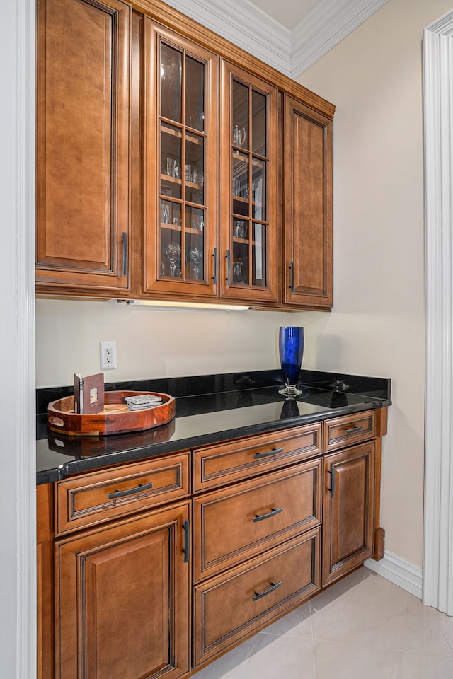 kitchen featuring light tile patterned floors, ornamental molding, and dark stone counters