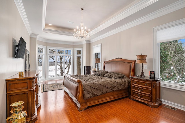 bedroom featuring a tray ceiling, light hardwood / wood-style floors, and ornamental molding