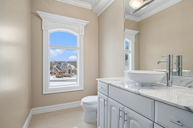 bathroom featuring vanity, crown molding, toilet, and baseboards