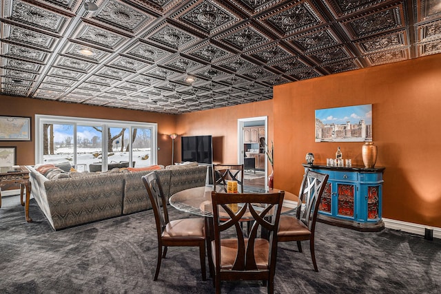 carpeted dining room featuring baseboards and an ornate ceiling