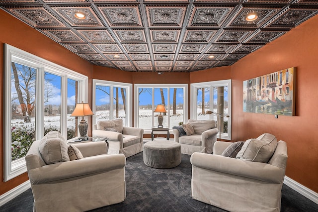 living area featuring baseboards and an ornate ceiling