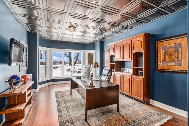 office area with dark wood-style flooring, baseboards, and an ornate ceiling