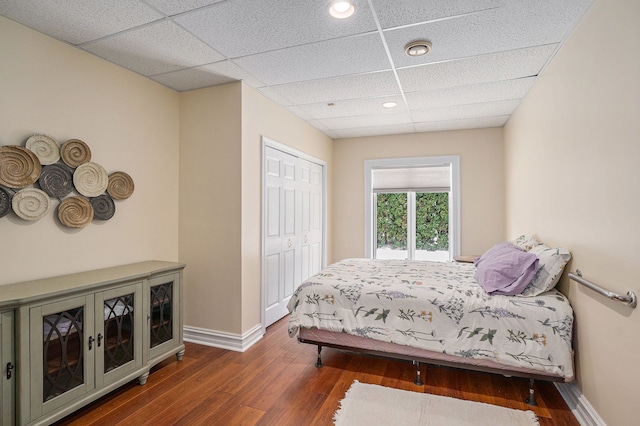 bedroom with baseboards, a drop ceiling, recessed lighting, wood finished floors, and a closet