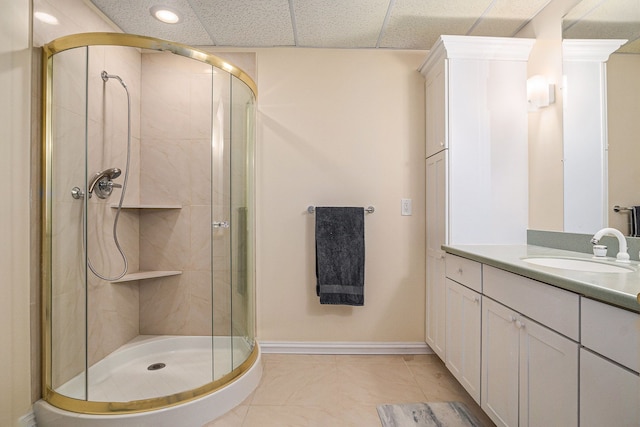 full bath featuring a paneled ceiling, baseboards, vanity, and a shower stall