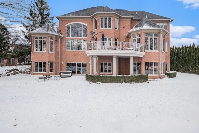 snow covered house with brick siding and a balcony