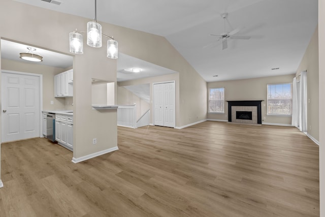 unfurnished living room featuring ceiling fan, a fireplace, light hardwood / wood-style floors, and vaulted ceiling