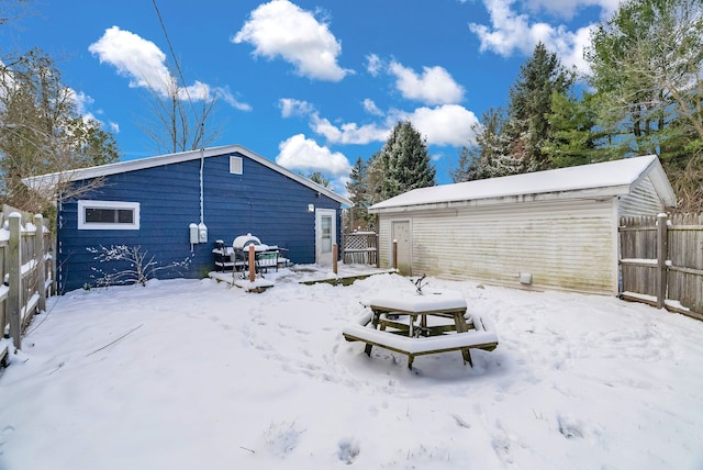 snow covered rear of property featuring an outbuilding