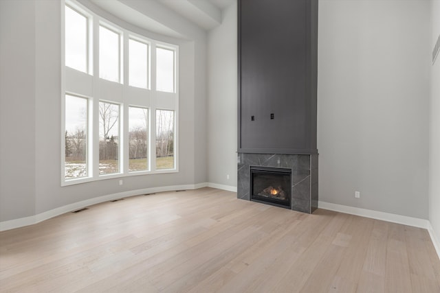 unfurnished living room featuring a tile fireplace and light hardwood / wood-style flooring