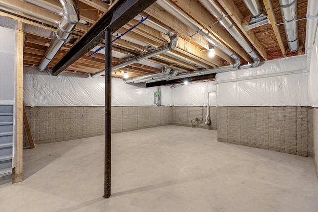 basement featuring electric panel and brick wall