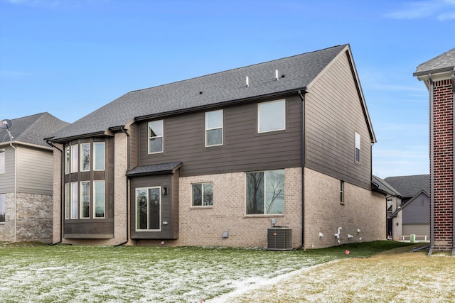 rear view of property featuring a lawn and cooling unit