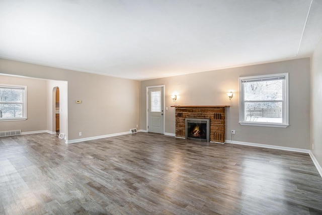 unfurnished living room featuring ornamental molding and dark wood-type flooring