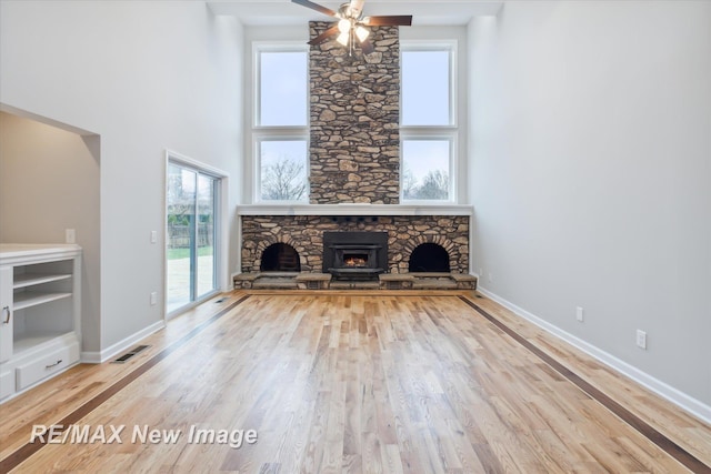 unfurnished living room featuring ceiling fan, wood-type flooring, and a fireplace