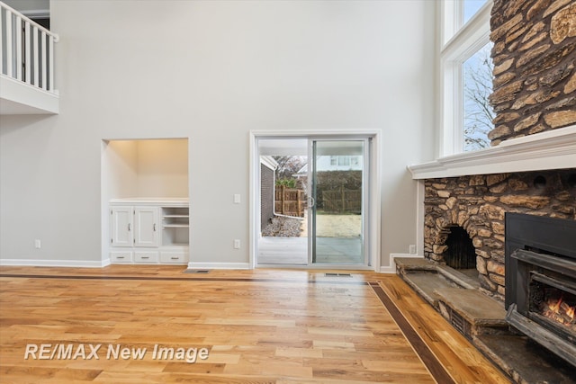 60 Golfview Dr, Saginaw, MI 48638 - unfurnished living room featuring a high ceiling, a stone fireplace, wood finished floors, and baseboards