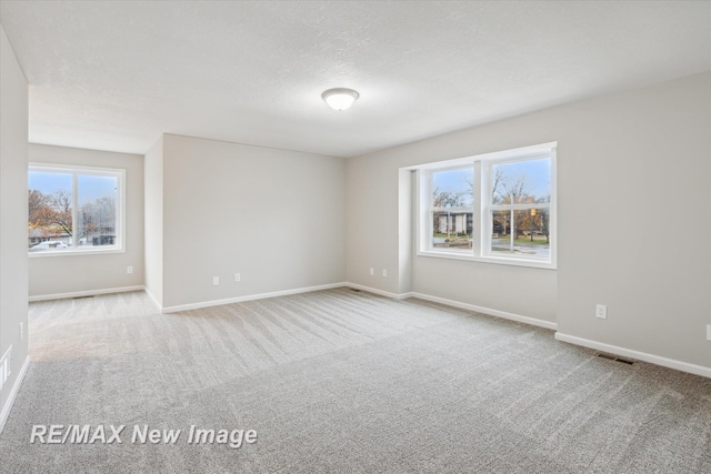 spare room featuring a textured ceiling and light carpet