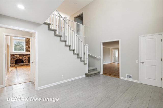 stairs with a fireplace, wood-type flooring, and a towering ceiling