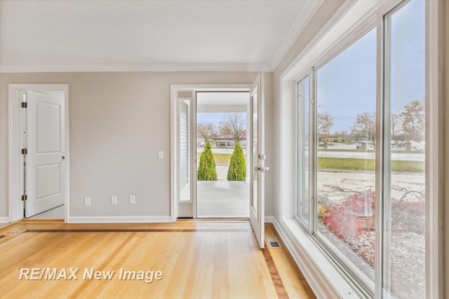 doorway to outside featuring ornamental molding and light wood-type flooring