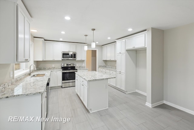 kitchen with sink, hanging light fixtures, a kitchen island, white cabinets, and appliances with stainless steel finishes