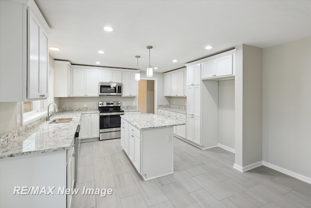 60 Golfview Dr, Saginaw, MI 48638 - kitchen with stainless steel appliances, a sink, a center island, baseboards, and white cabinets