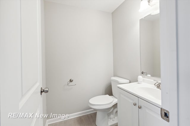 bathroom with hardwood / wood-style flooring, vanity, and toilet