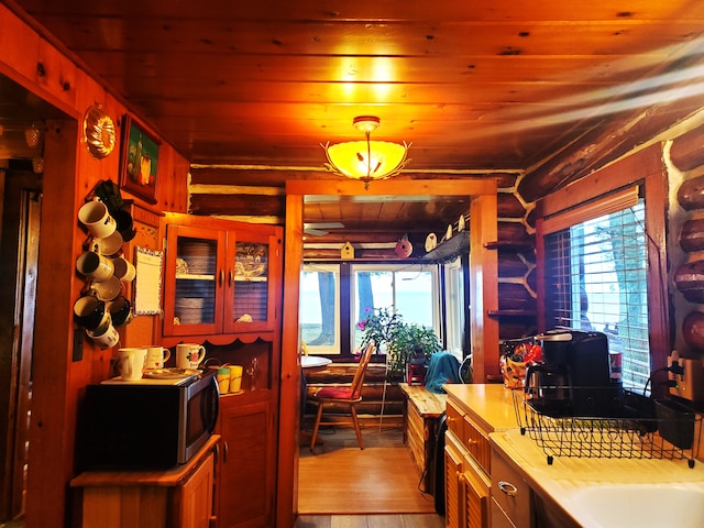 kitchen with light hardwood / wood-style floors, rustic walls, hanging light fixtures, and wood ceiling